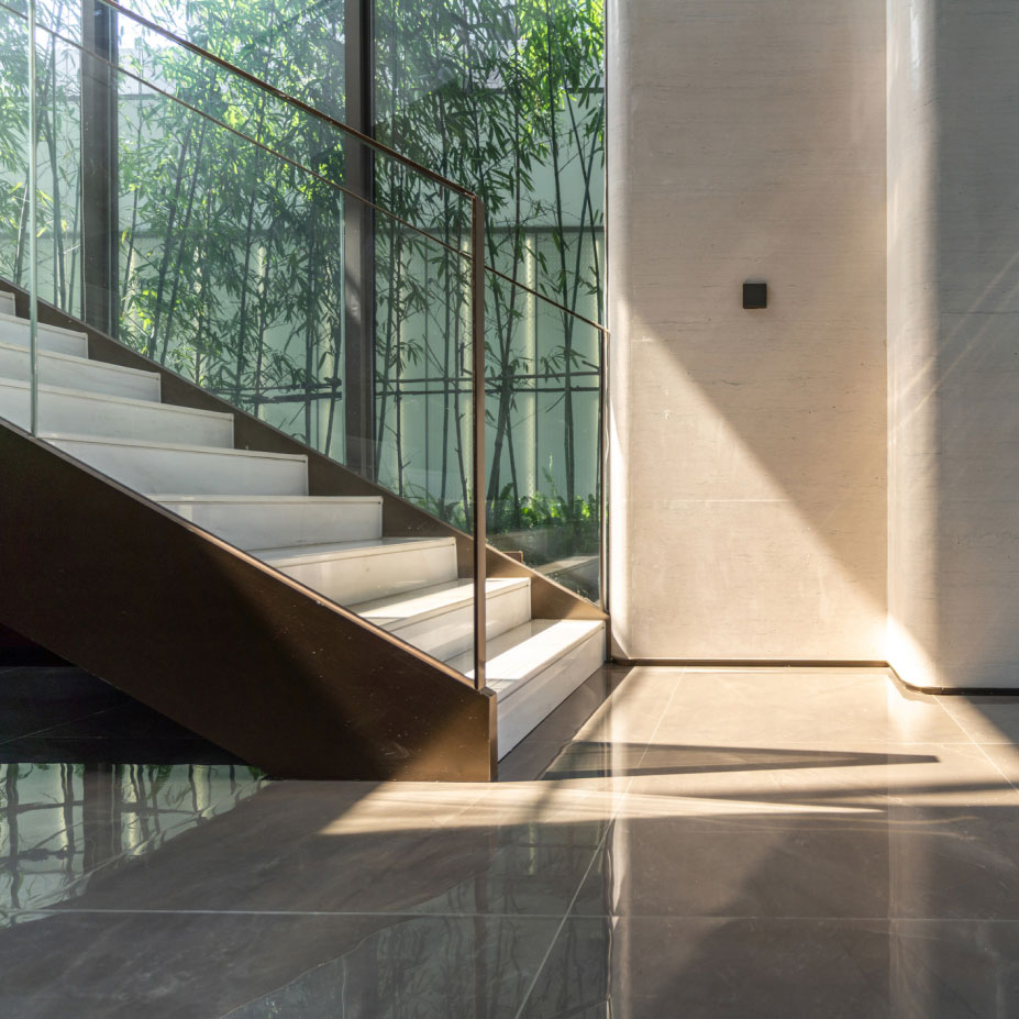 Modern staircase engulfed in sun beams and bamboo trees outside in the background.